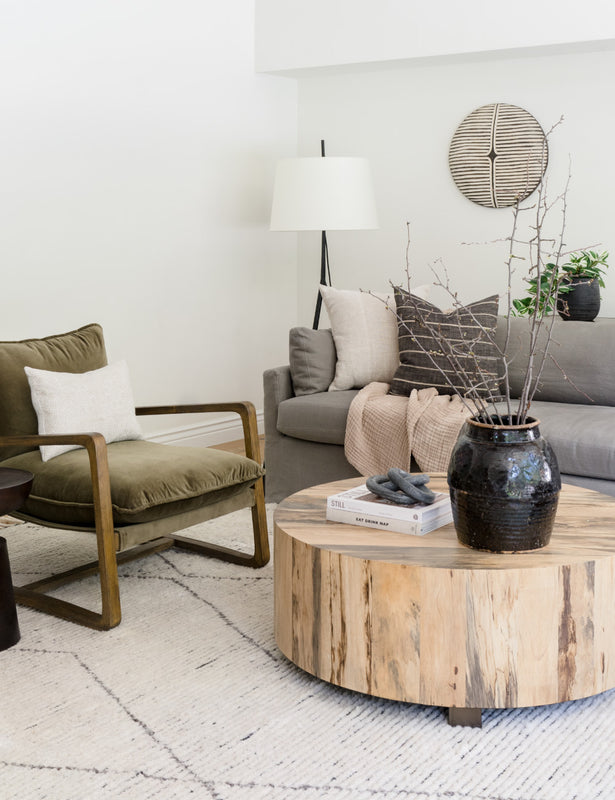 Neutral lounge room with olive green velvet armchair, round solid timber coffee table and grey sofa